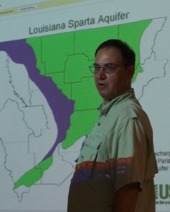 Dr. Bill Patterson presenting in front of a projected map titled 'Louisiana Sparta Aquifer,' highlighting areas in green and purple.
